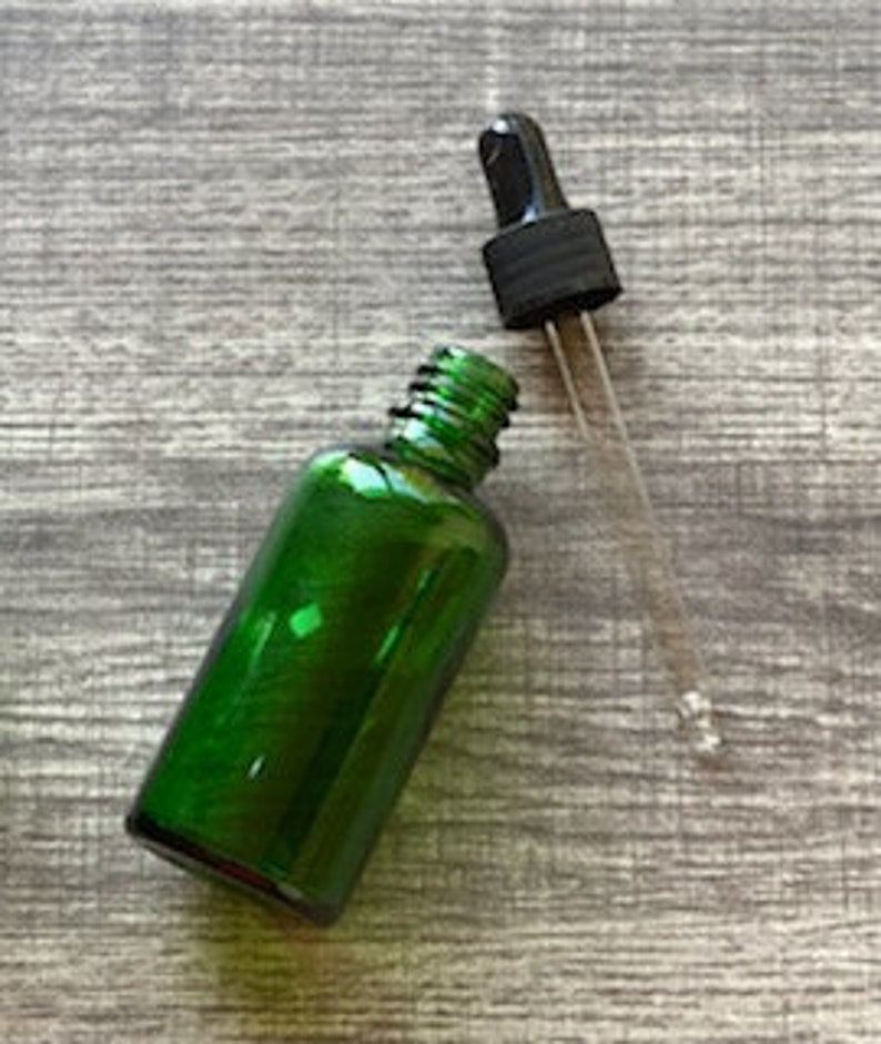 Peut inclure: Une bouteille en verre vert avec un bouchon compte-gouttes noir. La bouteille est vide et pr&ecirc;te &agrave; &ecirc;tre remplie d'huiles essentielles ou d'autres liquides.