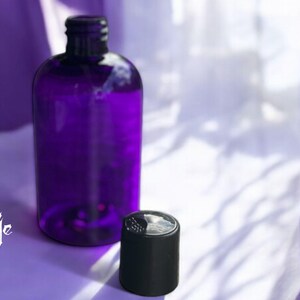 May include: A purple glass bottle with a black lid. The bottle is sitting on a purple surface.