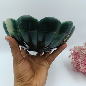 May include: A green and white stone bowl with a scalloped edge. The bowl is carved in the shape of a flower.
