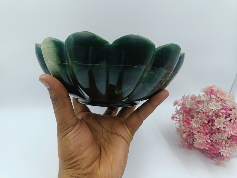 May include: A green and white stone bowl with a scalloped edge. The bowl is carved in the shape of a flower.