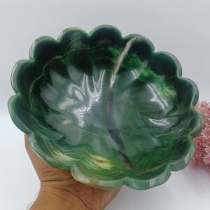 May include: A green jade bowl with a scalloped edge. The bowl is carved to resemble a leaf and has a natural, organic look.