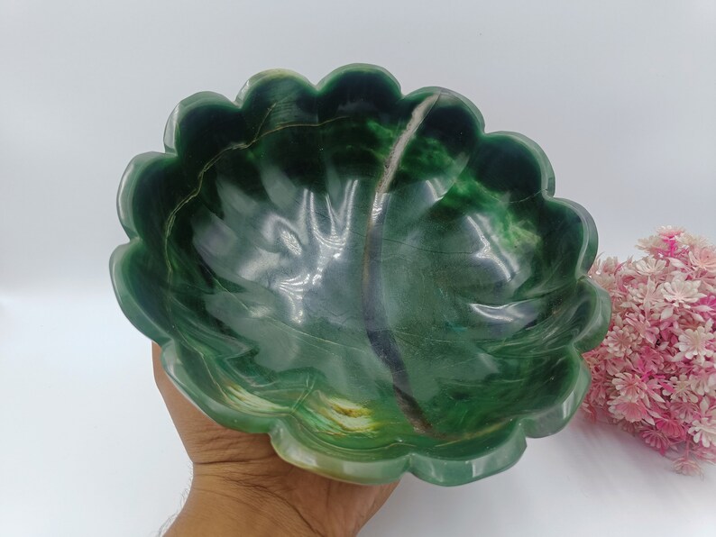 May include: A green jade bowl with a scalloped edge. The bowl is carved to resemble a leaf and has a natural, organic look.