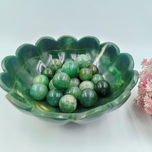 May include: A green jade bowl with a scalloped edge filled with green jade spheres.