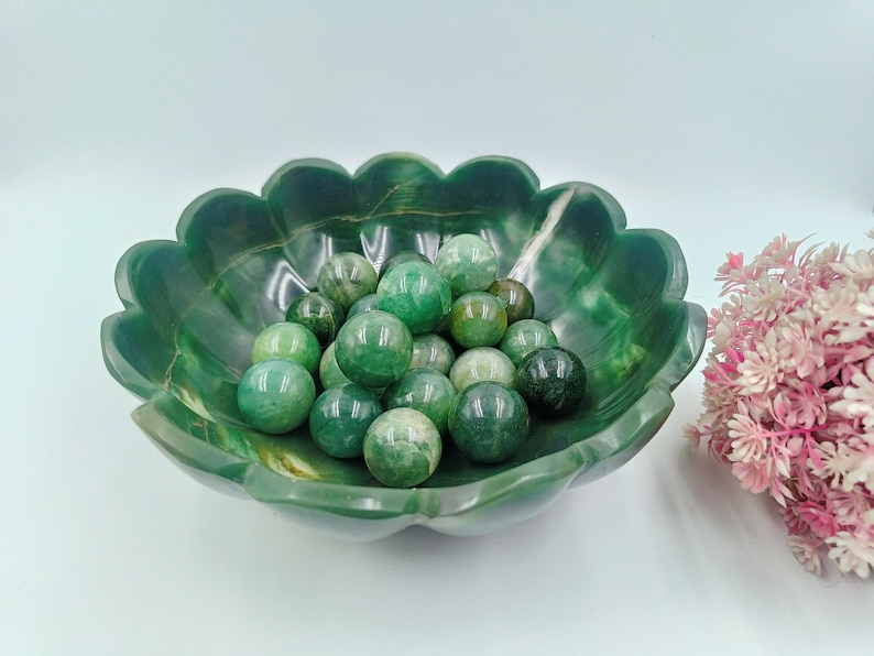 May include: A green jade bowl with a scalloped edge filled with green jade spheres.
