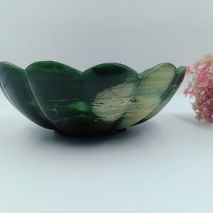 May include: A green and white stone bowl with a scalloped edge. The bowl is made from natural materials and has a unique, organic shape.