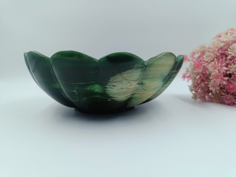 May include: A green and white stone bowl with a scalloped edge. The bowl is made from natural materials and has a unique, organic shape.