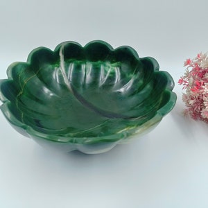 May include: A green stone bowl with a scalloped edge. The bowl is made of a type of green marble with white veins running through it.