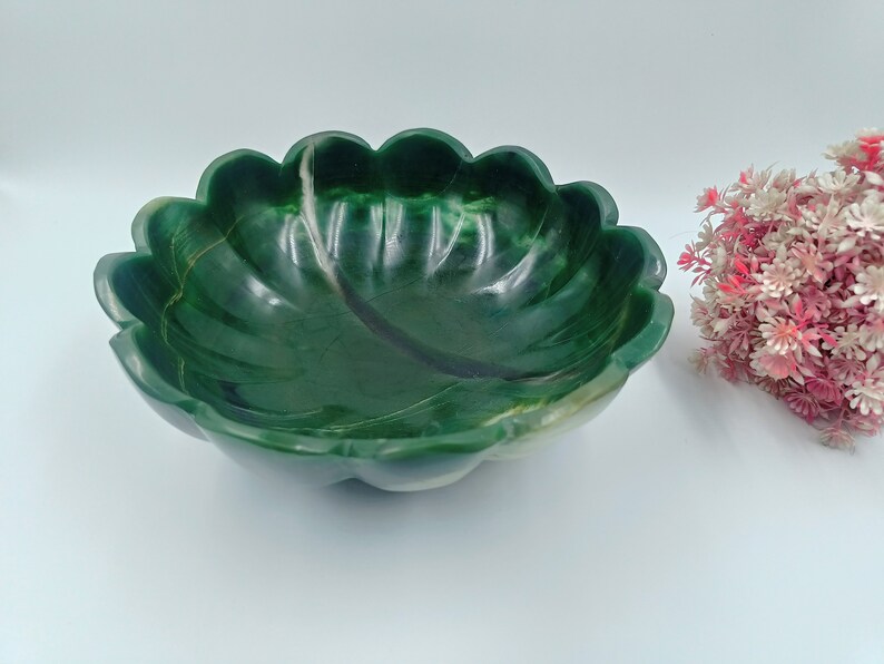 May include: A green stone bowl with a scalloped edge. The bowl is made of a type of green marble with white veins running through it.
