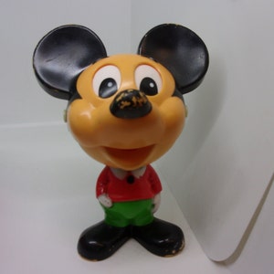 Puede incluir: Una figura vintage de plástico de Mickey Mouse con orejas negras, cara amarilla, camisa roja y pantalones verdes.