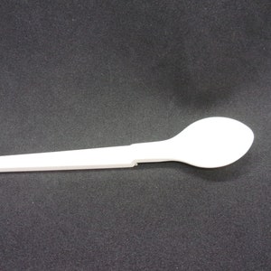 May include: A white plastic spoon with a long handle. The spoon is designed to be disposable.