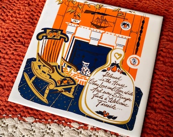 May include: A square, decorative tile with a vintage illustration. The design features a rocking chair, fireplace, and a cat, with the text "Blessed is the House Where Love and Cheer abide..." in a decorative font. The color palette includes orange, blue, and gold.