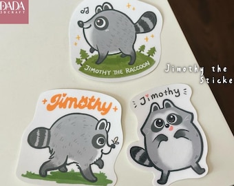 May include: Three die-cut vinyl stickers featuring a cartoon raccoon named Jimothy. One sticker shows the raccoon on green grass with the text Jimothy the Raccoon. Another shows the raccoon with the orange text Jimothy. The third shows Jimothy.