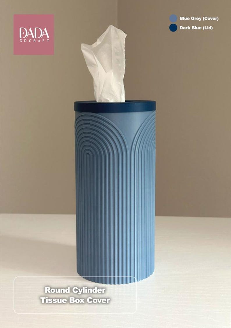 K&ouml;nnte beinhalten: Ein blau-grauer, zylindrischer Taschentuchbox-Bezug mit dunkelblauem Deckel und vertikaler, bogenf&ouml;rmiger Rippenstruktur. Das Produkt ist mit DADA 3DCRAFT und Round Cylinder Tissue Box Cover beschriftet. Ein wei&szlig;es Taschentuch ragt oben heraus.
