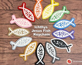 May include: A collection of twelve Ichthys Jesus Fish keychains in various colors including red, orange, yellow, green, blue, purple, black, gray, white, gold, and pink. Each keychain features the word JESUS cut out from the center of the fish shape.