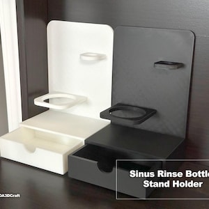 May include: A white and a black plastic stand with a drawer and two shelves for holding sinus rinse bottles. The stand is labeled "Sinus Rinse Bottle Stand Holder".