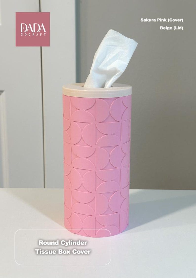 K&ouml;nnte beinhalten: Ein zylindrischer Taschentuchbox-Bezug in Sakura-Pink mit beigem Deckel. Die Au&szlig;enseite zeigt ein sich wiederholendes geometrisches Muster aus Halbkreisen. Ein wei&szlig;es Taschentuch ragt aus der oberen &Ouml;ffnung. Der Text DADA 3D CRAFT und Round Cylinder Tissue Box Cover sind zu sehen.