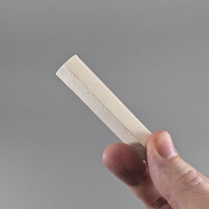 May include: A white chalk stick held in a hand.