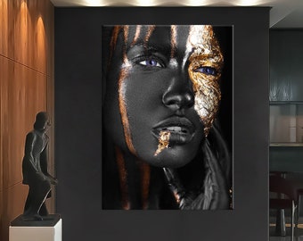 May include: A striking portrait of a person with black skin, adorned with gold leaf and streaks of gold paint. The person has blue eyes and is set against a dark background, creating a dramatic and artistic effect. The artwork is displayed in a modern interior.