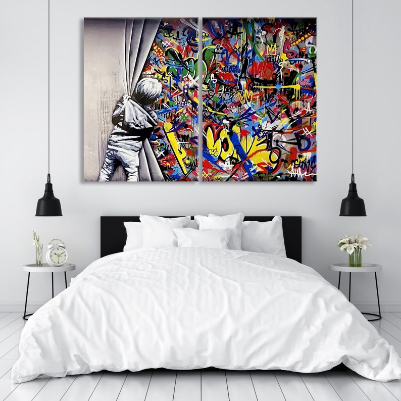 Op de afbeelding: Een gesplitst canvas schilderij dat een kind laat zien dat door een wit gordijn naar een kleurrijke graffitimuur kijkt. De graffiti heeft een verscheidenheid aan kleuren, waaronder rood, geel, blauw, groen en zwart. Het kind draagt een wit shirt en een blauwe jeans.
