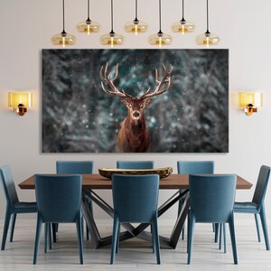 K&ouml;nnte beinhalten: Ein gro&szlig;er Leinwanddruck eines Rothirsches mit Geweih, der in einem schneebedeckten Wald steht. Der Druck h&auml;ngt an einer Wand &uuml;ber einem Esstisch aus Holz mit blauen St&uuml;hlen.