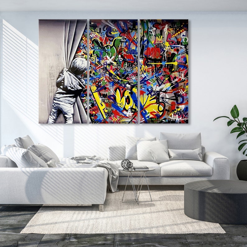 Op de afbeelding: Een driedelig canvasprint met een kind dat achter een wit gordijn vandaan kijkt. De achtergrond is een kleurrijk abstract ontwerp met graffiti-achtige letters en symbolen.