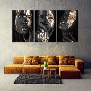 K&ouml;nnte beinhalten: Ein dreiteiliges Wandbild-Set aus Leinwand mit einem Schwarz-Gold-Portr&auml;t einer Frau. Das Gesicht der Frau ist mit Blattgold bemalt und ihre Augen sind geschlossen. Der Hintergrund ist schwarz.