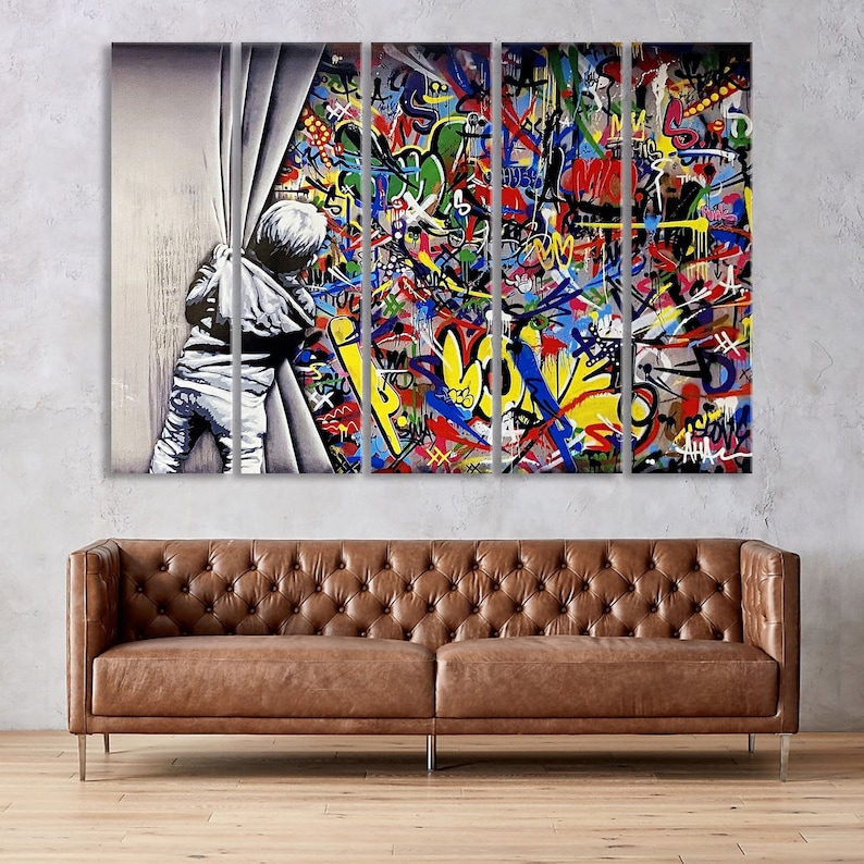Op de afbeelding: Een kleurrijke graffitimuur met een kind dat uit een wit gordijn gluurt. De muurschildering heeft een verscheidenheid aan kleuren, waaronder rood, geel, blauw, groen en zwart.