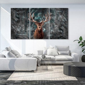 K&ouml;nnte beinhalten: Ein Rothirsch mit gro&szlig;en Geweih steht in einem verschneiten Wald. Der Hirsch schaut direkt in die Kamera. Der Hintergrund ist ein verschwommener Wald mit fallendem Schnee.