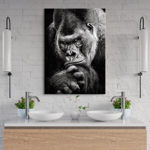 May include: Black and white photograph of a gorilla looking thoughtful with its chin resting on its hand.