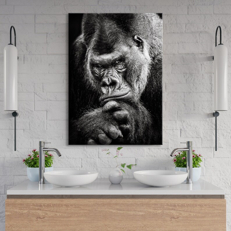 May include: Black and white photograph of a gorilla looking thoughtful with its chin resting on its hand.