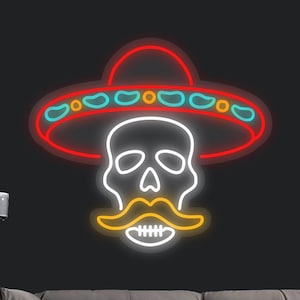 May include: Neon sign depicting a white skull wearing a red sombrero with a yellow mustache. The sign is mounted on a black wall above a gray couch.