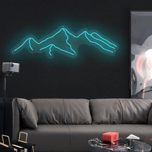 May include: A teal blue neon sign depicting a mountain range on a black wall. The sign is hanging above a grey leather sofa and a black coffee table.