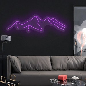 May include: A purple neon sign depicting a mountain range silhouette. The sign is mounted on a black wall above a grey leather sofa.