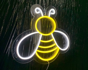 May include: A white neon bee with yellow accents. The bee is outlined in white and has a yellow body with black stripes. The bee is hanging from a wire.
