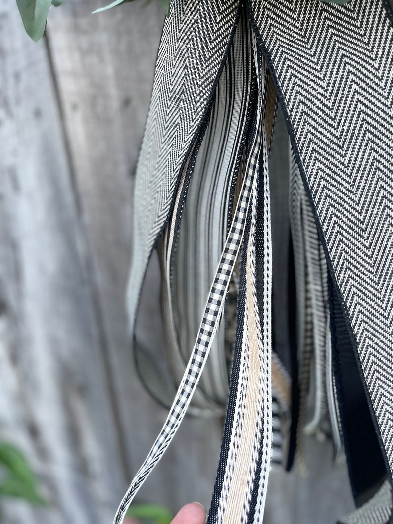 K&ouml;nnte beinhalten: Nahaufnahme einer Sammlung dekorativer B&auml;nder in verschiedenen Mustern und Texturen. Die B&auml;nder weisen schwarz-wei&szlig;e Designs auf, darunter Fischgr&auml;tenmuster, Streifen und Vichy-Karo. Einige B&auml;nder sind einfarbig schwarz oder beige. Die B&auml;nder werden wahrscheinlich zum Basteln oder Dekorieren verwendet.