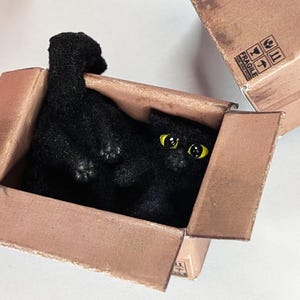 Miniature cat in box, pet in 1:12 twelfth scale for doll house of diorama. Fluffy black funny kitten toy. Square feline