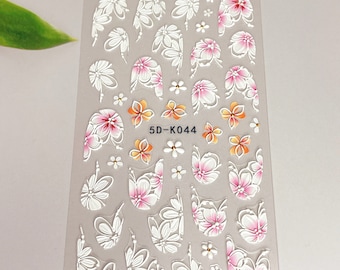 Puede incluir: Una hoja de pegatinas para uñas blancas con diseños florales rosas y naranjas. La hoja tiene el texto "5D-K044" impreso en ella.