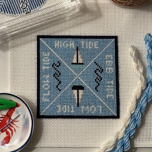 May include: A blue and white needlepoint canvas with the text "High Time To Sail North" and images of a sailboat and seahorses.