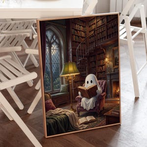 Puede incluir: Una impresi&oacute;n rectangular enmarcada que representa a un fantasma blanco sentado en un sill&oacute;n morado dentro de una biblioteca, leyendo un libro abierto. La escena incluye una l&aacute;mpara verde alta, una escalera de caracol, estanter&iacute;as y una ventana.