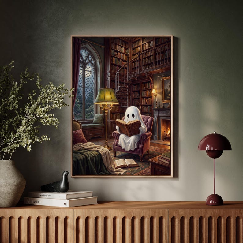 Puede incluir: Una impresi&oacute;n de arte mural enmarcada que representa una figura de fantasma blanca sentada en un sill&oacute;n de felpa, leyendo un libro dentro de una biblioteca. La escena incluye estanter&iacute;as altas, una escalera de caracol y una ventana.