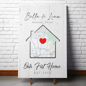 May include: A white wooden sign with the names "Bella & Liam" above "Houston, Texas." A house-shaped outline contains a map with a red heart. The text "Our First Home EST 2023" is below the house graphic.