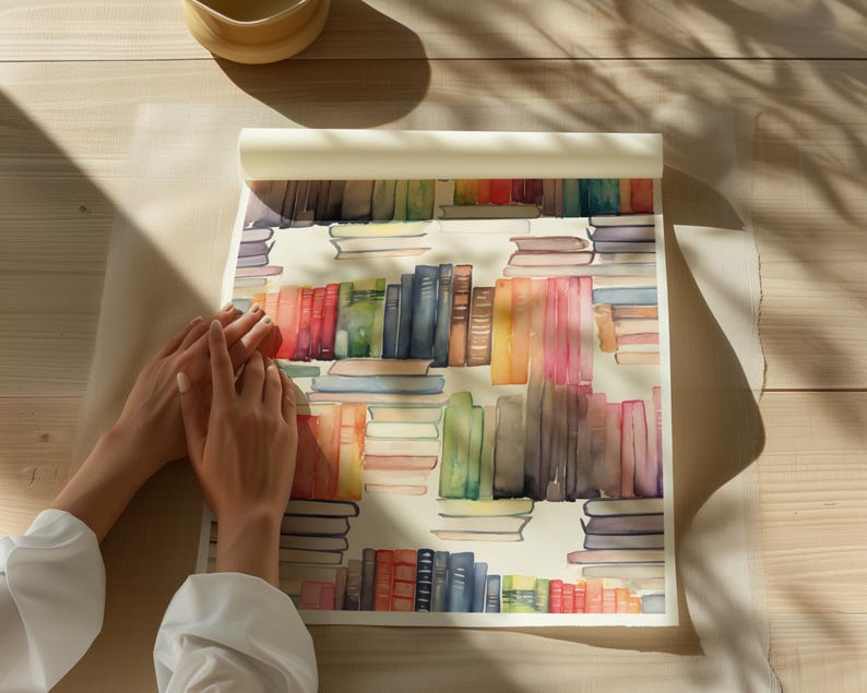 May include: Watercolor print featuring a repeating pattern of colorful books. The books are arranged in stacks and rows, with a variety of colors including red, blue, green, and orange. The print is on a roll of paper, with a light-colored background.