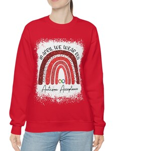 Może przedstawiać: Czerwona bluza z nadrukiem tęczy i tekstem "In April We Wear Red Autism Acceptance".