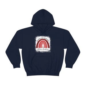 May include: Navy blue hoodie with a red glitter rainbow and the text "In April We Wear Red Autism Acceptance".