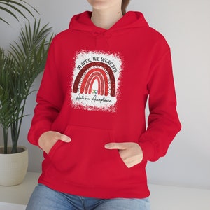 May include: Red hoodie with a rainbow design and the text "In April we wear red Autism Acceptance".