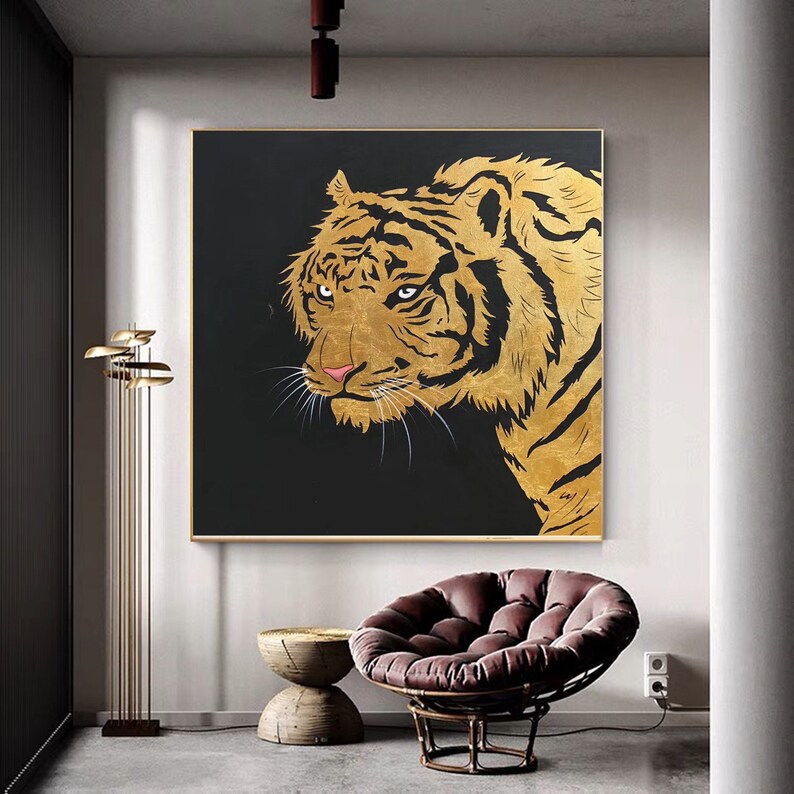 May include: A gold and black painting of a tiger's head and shoulders. The tiger is looking directly at the viewer with a fierce expression. The painting is set against a dark background.