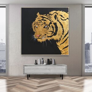 May include: A close-up of a golden tiger's face against a black background. The tiger's fur is detailed with gold paint and its eyes are a deep brown.
