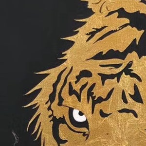 May include: Close-up of a gold tiger's eye with black stripes. The eye is partially open and the tiger's fur is textured.