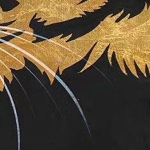 May include: Close-up of a black and gold cat illustration. The cat's fur is depicted with gold paint, and its whiskers are white.