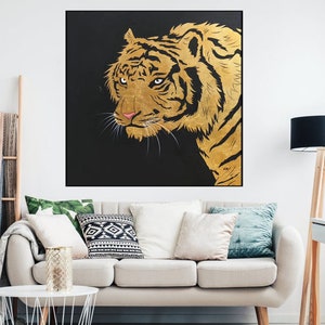May include: A close-up of a golden tiger's face against a black background. The tiger's fur is detailed with gold paint and the eyes are a deep, dark brown.